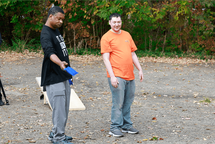 Two adults playing a bean bag toss game outside