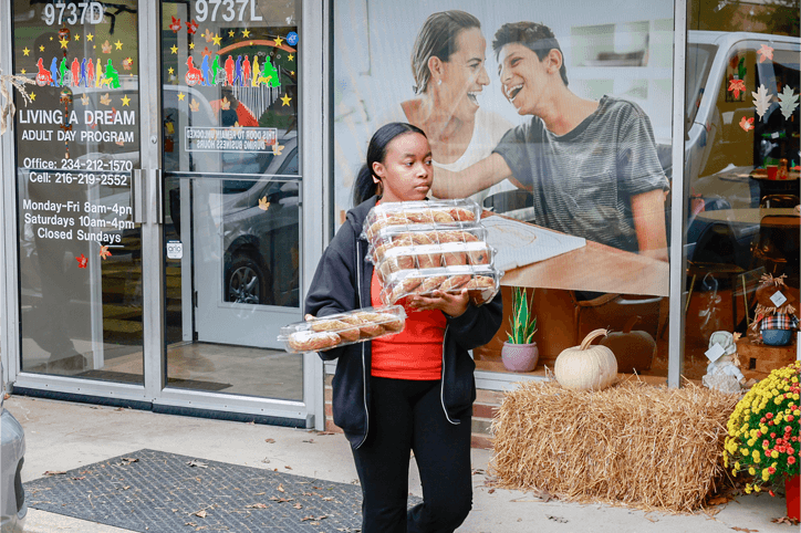 Staff member carrying a stack of baked goods