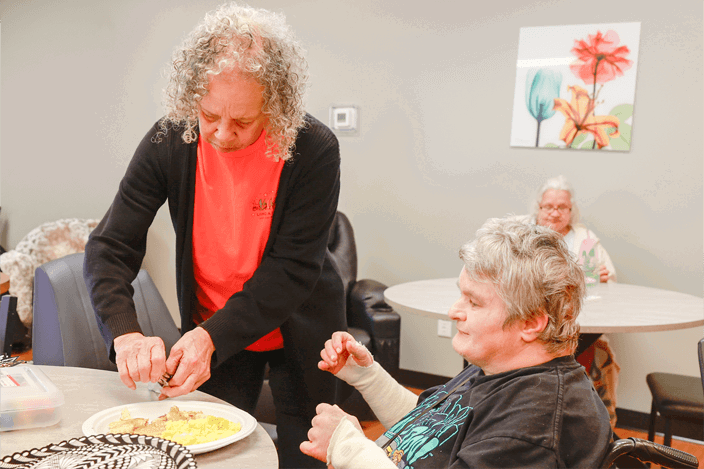A staff member helping an older woman with her meal