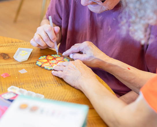 Older woman being helped with a craft