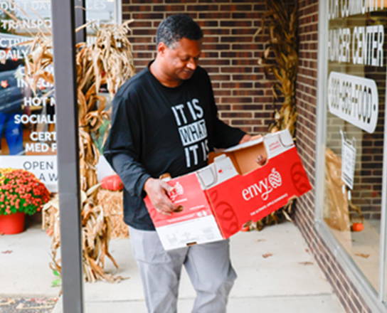 Adult carrying a box into a hunger center