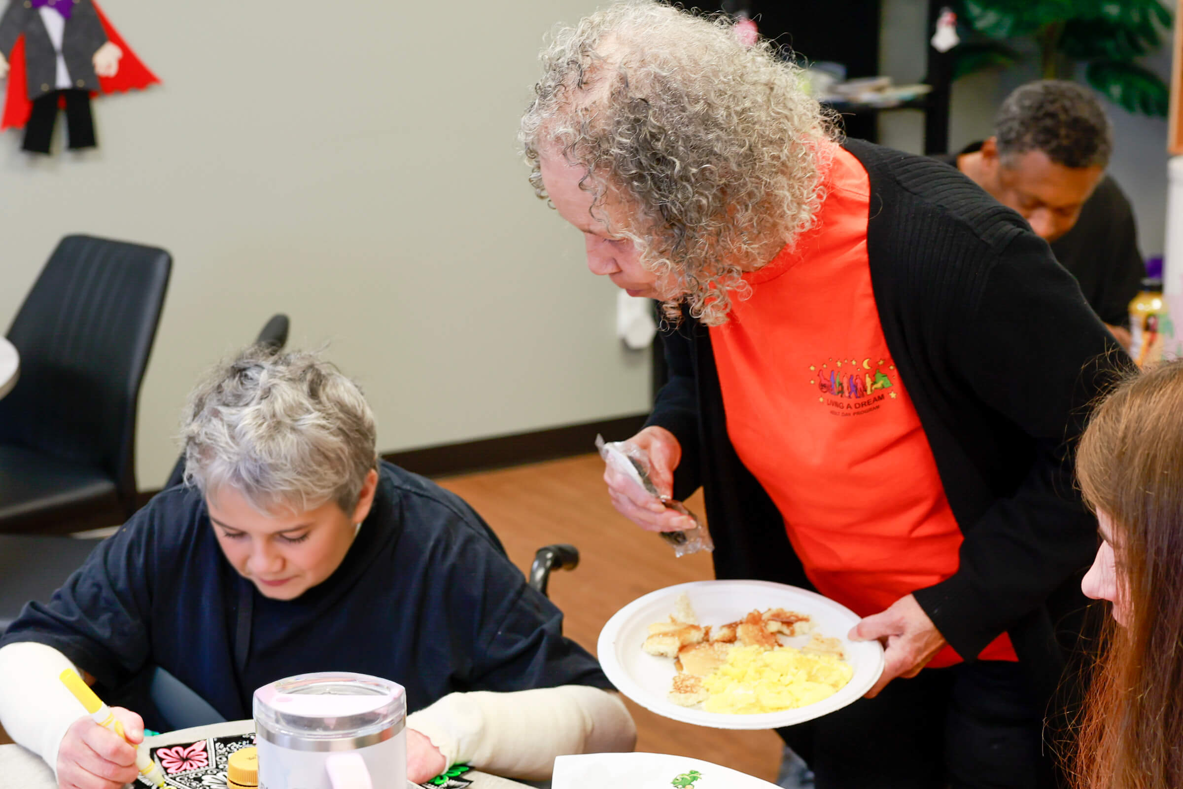 Staff member serving a plate of food to a smiling participant